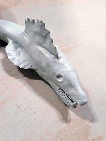 A ceramic sculpture of a barracuda fins bent in motion painted with matte sky blue spray paint