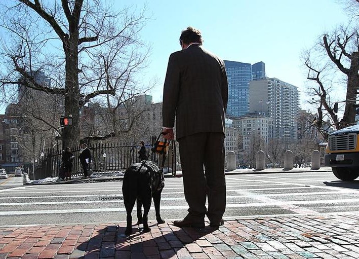 Blind and hearing-impaired, Carl Richardson stood at a crosswalk in front of the State House that has no ramp.