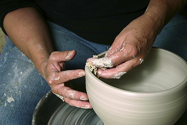 Man spinning pottery wheel